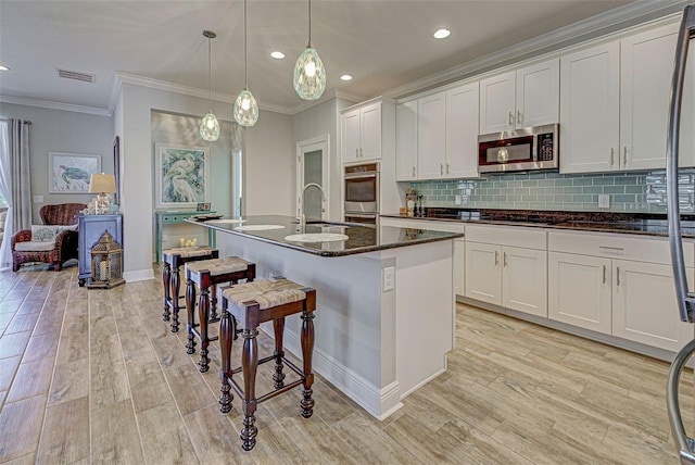 kitchen with pendant lighting, a center island with sink, white cabinetry, and sink