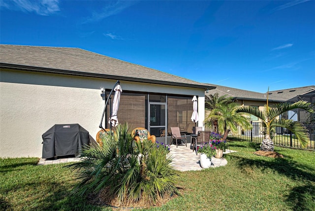 back of property with a lawn, a patio area, and a sunroom