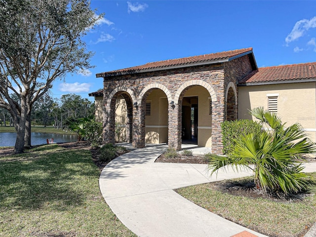 mediterranean / spanish home with a water view and a front lawn