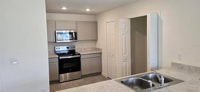 kitchen with dark wood-type flooring, appliances with stainless steel finishes, sink, and gray cabinets