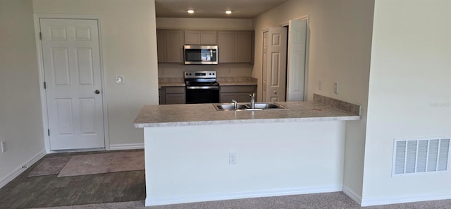 kitchen with kitchen peninsula, appliances with stainless steel finishes, gray cabinetry, carpet floors, and sink