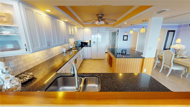 kitchen featuring a tray ceiling, sink, white cabinets, and pendant lighting