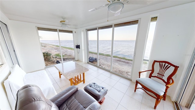 sunroom featuring ceiling fan and a water view