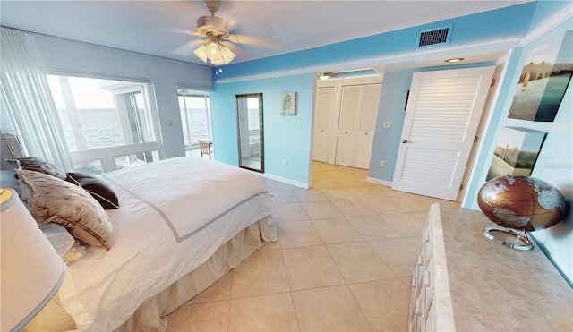 bedroom with ceiling fan, a water view, and light tile patterned floors