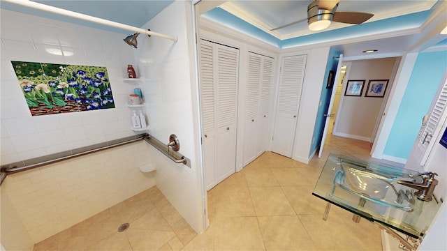 hall featuring light tile patterned flooring, crown molding, and a tray ceiling