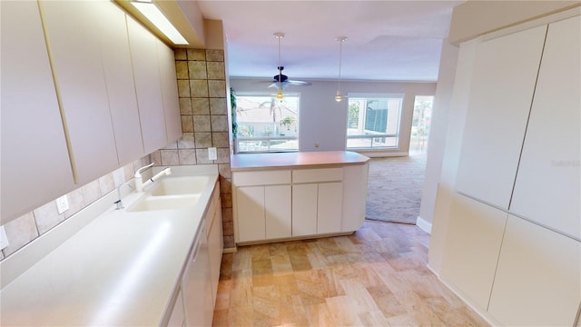 kitchen with sink, hanging light fixtures, white dishwasher, ceiling fan, and white cabinets