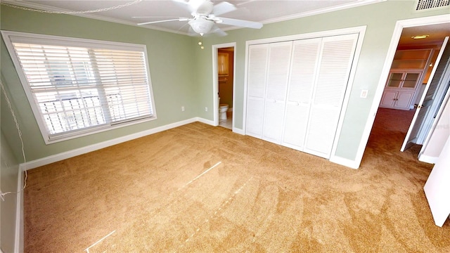 unfurnished bedroom with crown molding, light colored carpet, ceiling fan, and a closet