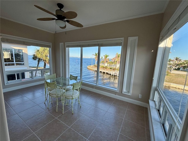 unfurnished sunroom featuring ceiling fan and a water view