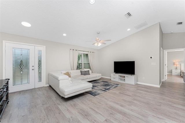 living room featuring ceiling fan, lofted ceiling, a textured ceiling, and light hardwood / wood-style flooring