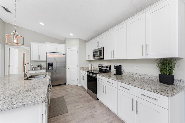 kitchen featuring stainless steel appliances, sink, decorative light fixtures, white cabinetry, and lofted ceiling