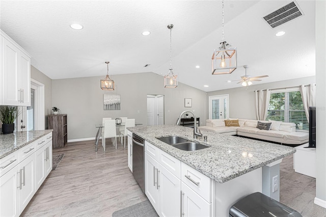 kitchen featuring white cabinets, stainless steel dishwasher, sink, and an island with sink