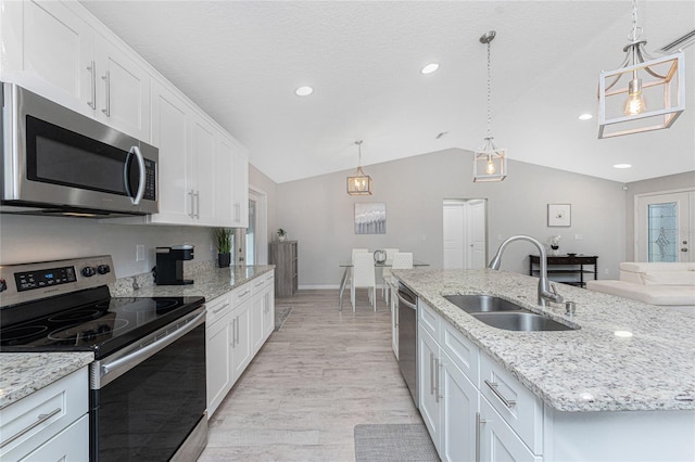 kitchen with a center island with sink, sink, appliances with stainless steel finishes, decorative light fixtures, and white cabinetry