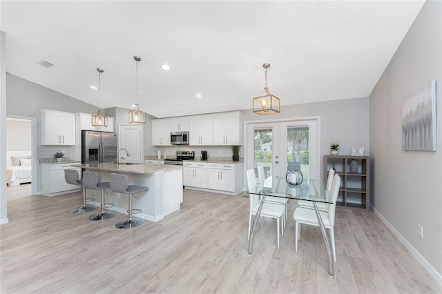 kitchen featuring pendant lighting, white cabinetry, stainless steel appliances, and a kitchen island with sink