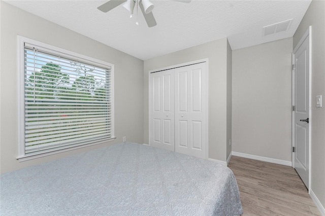 bedroom featuring ceiling fan, light hardwood / wood-style floors, a textured ceiling, and a closet