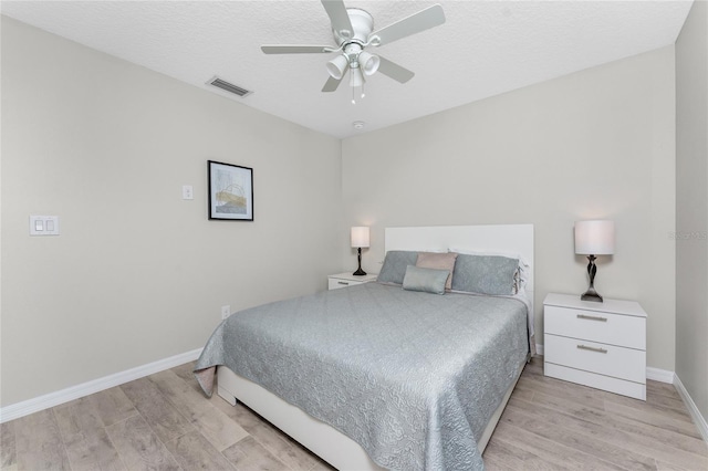 bedroom with ceiling fan, light hardwood / wood-style floors, and a textured ceiling