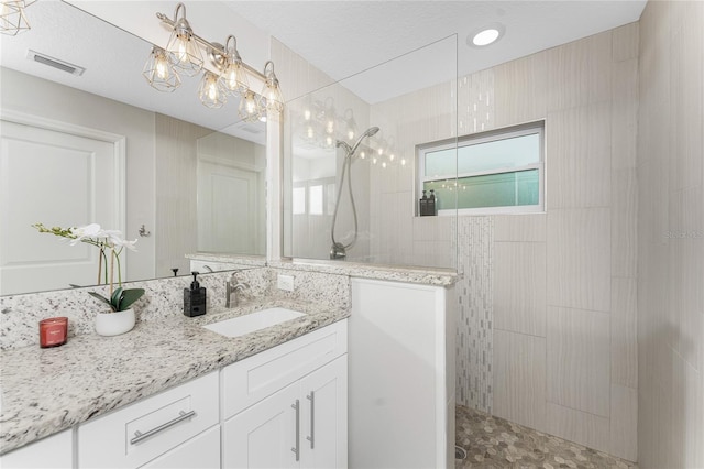 bathroom with vanity and tiled shower