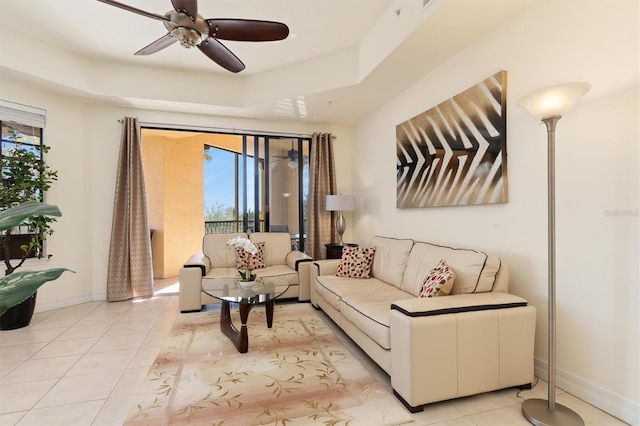 living room featuring light tile patterned floors, a raised ceiling, ceiling fan, and a healthy amount of sunlight