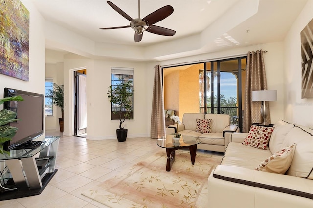 tiled living room featuring a raised ceiling and ceiling fan