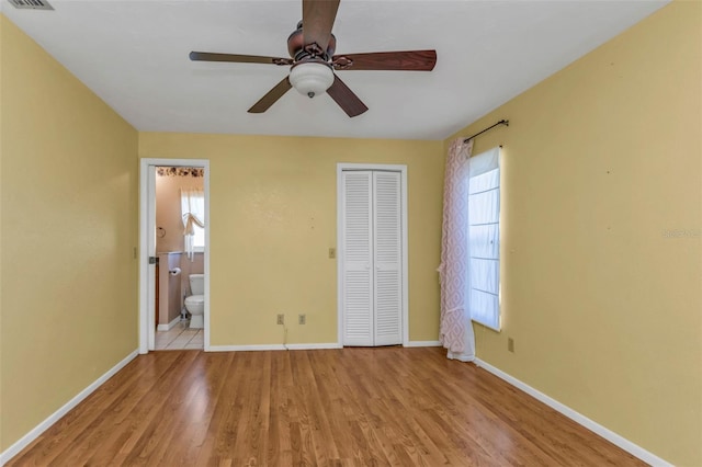 unfurnished bedroom featuring light hardwood / wood-style floors, a closet, ceiling fan, and ensuite bathroom