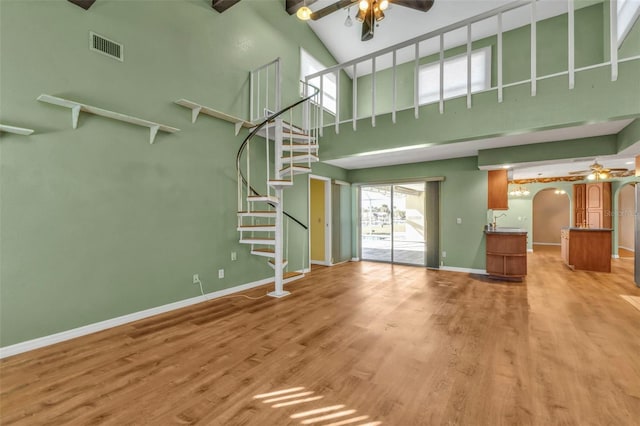 unfurnished living room featuring light hardwood / wood-style flooring, high vaulted ceiling, and ceiling fan