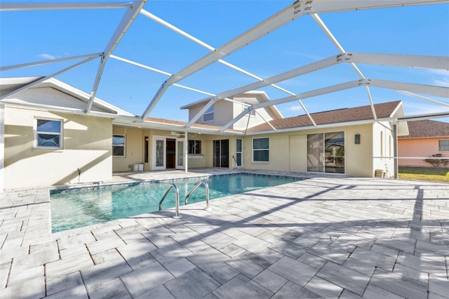 view of swimming pool with ceiling fan, glass enclosure, and a patio area