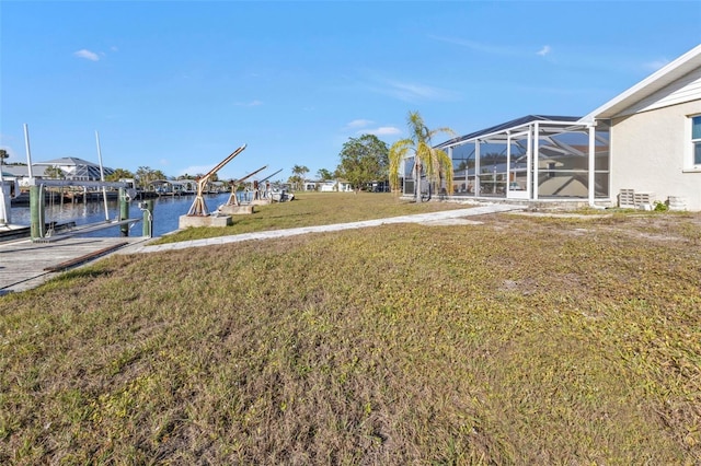 view of yard featuring a water view, a dock, and glass enclosure