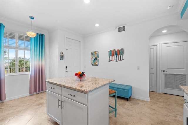 kitchen with light stone counters, ornamental molding, light tile patterned floors, a center island, and hanging light fixtures