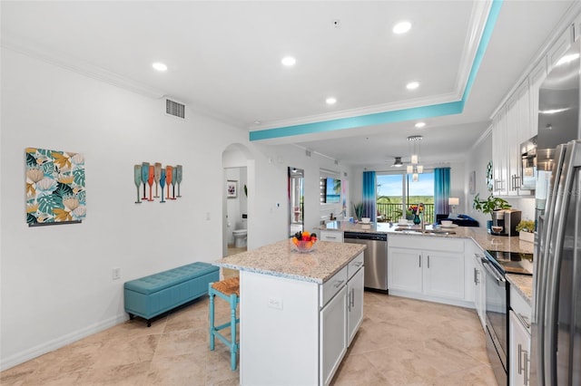 kitchen with white cabinetry, stainless steel appliances, kitchen peninsula, a breakfast bar, and a kitchen island