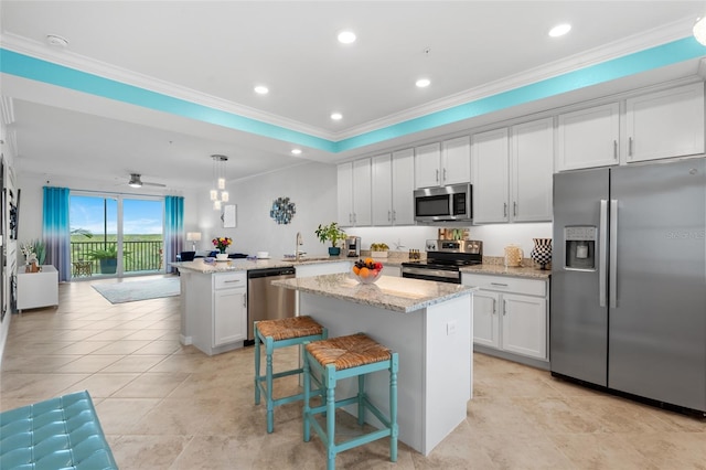 kitchen with white cabinets, decorative light fixtures, a kitchen island, and appliances with stainless steel finishes