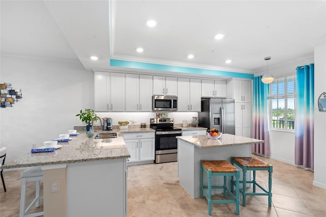 kitchen featuring white cabinets, a kitchen breakfast bar, stainless steel appliances, and decorative light fixtures