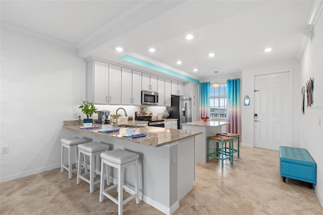 kitchen featuring white cabinetry, sink, kitchen peninsula, decorative light fixtures, and appliances with stainless steel finishes