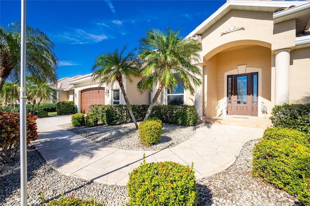 view of exterior entry featuring a garage and french doors