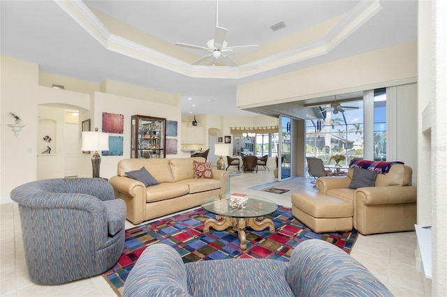 tiled living room featuring a raised ceiling, ceiling fan, and crown molding