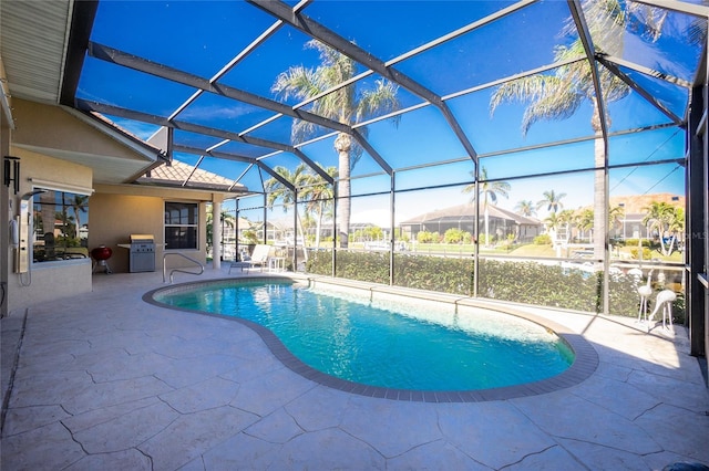 view of swimming pool with glass enclosure, a patio area, and grilling area