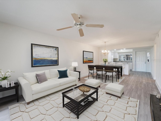 living room featuring light hardwood / wood-style floors and ceiling fan with notable chandelier