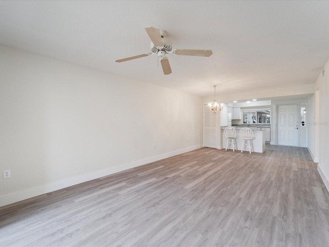 unfurnished living room with light hardwood / wood-style flooring and ceiling fan with notable chandelier