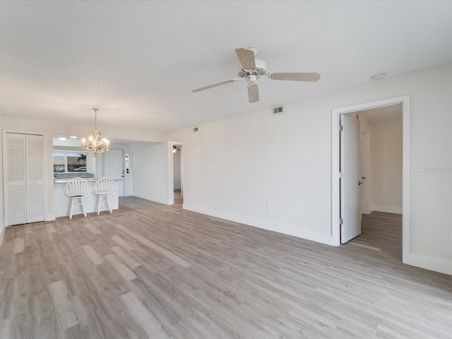 unfurnished living room featuring ceiling fan with notable chandelier and light wood-type flooring