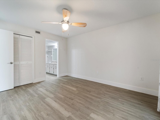 unfurnished bedroom featuring ensuite bath, ceiling fan, a closet, and light hardwood / wood-style flooring