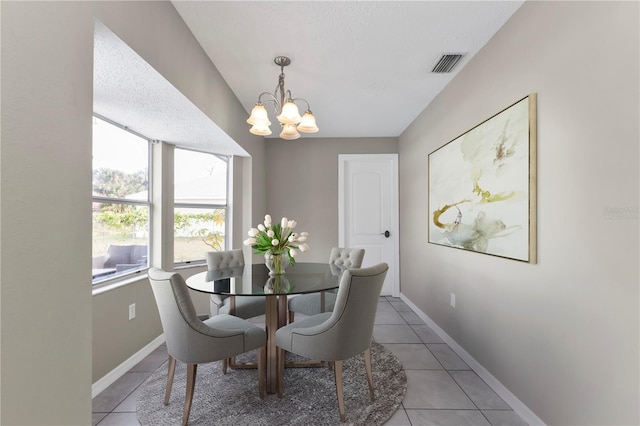 dining area with tile patterned flooring, a textured ceiling, and a notable chandelier