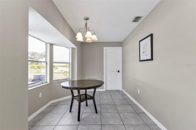 dining space featuring tile patterned flooring, a textured ceiling, and an inviting chandelier