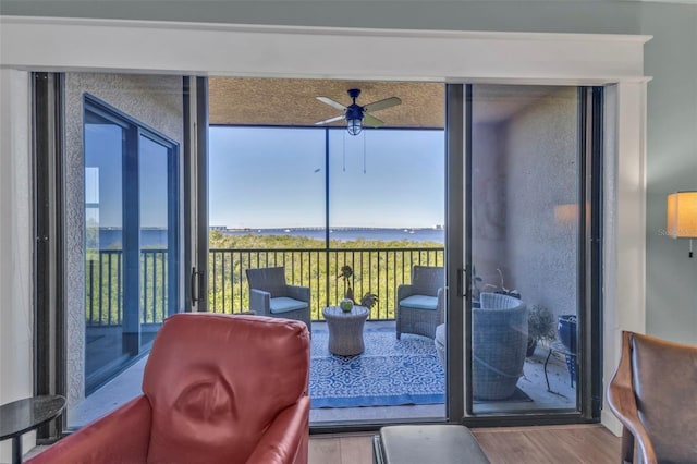 sunroom / solarium with ceiling fan and a water view