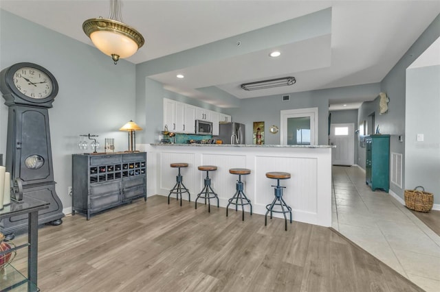 kitchen with white cabinetry, appliances with stainless steel finishes, kitchen peninsula, and light wood-type flooring