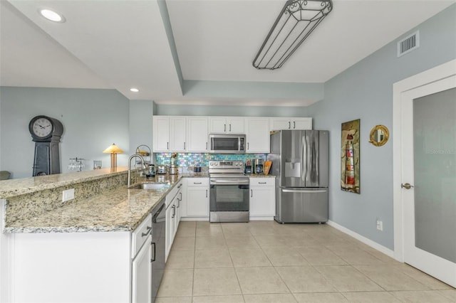 kitchen featuring sink, white cabinetry, appliances with stainless steel finishes, kitchen peninsula, and light stone countertops