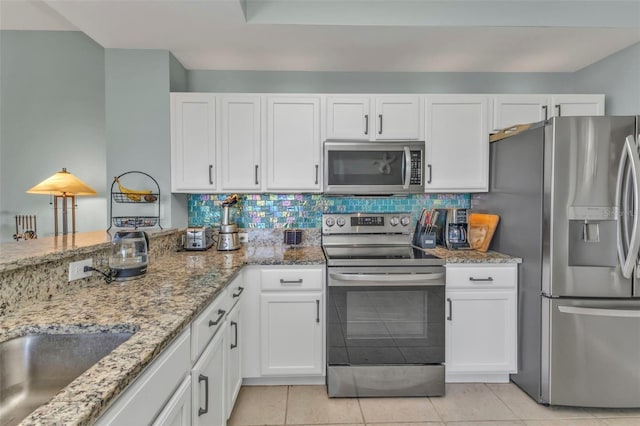 kitchen featuring white cabinetry, appliances with stainless steel finishes, decorative backsplash, and light tile patterned floors