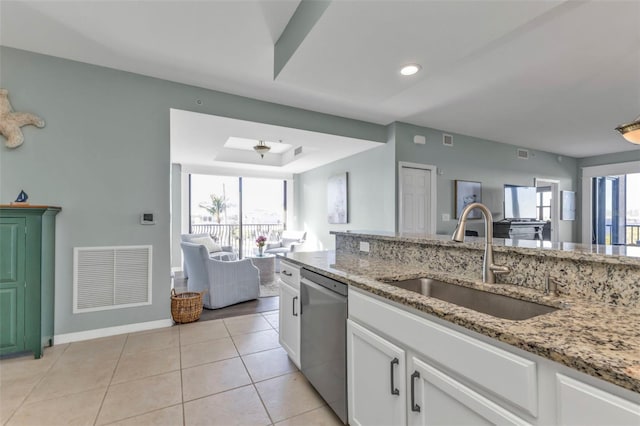 kitchen with plenty of natural light, sink, white cabinets, stainless steel dishwasher, and light stone countertops