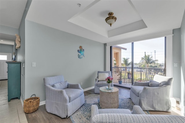 living room featuring a tray ceiling, floor to ceiling windows, and light wood-type flooring