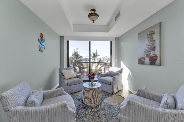 living room featuring expansive windows, wood-type flooring, and a tray ceiling