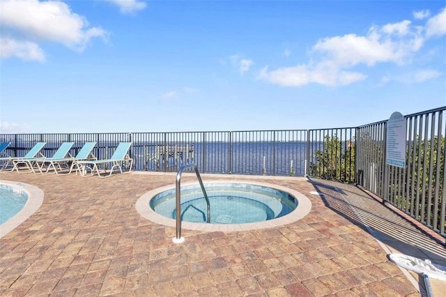 view of pool with a hot tub, a patio, and a water view