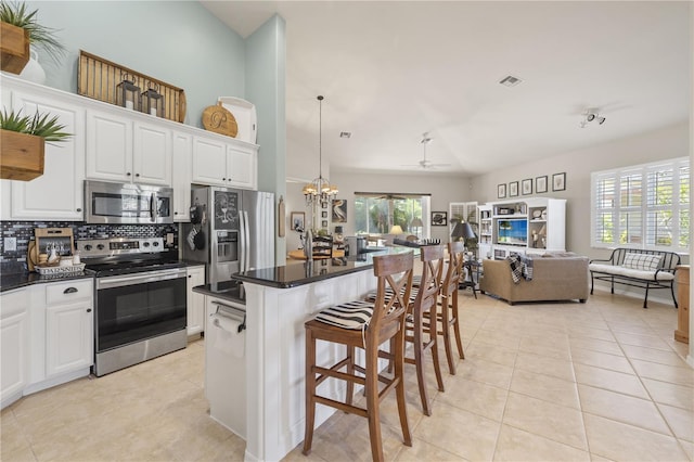 kitchen with a center island, white cabinets, a kitchen breakfast bar, a wealth of natural light, and stainless steel appliances