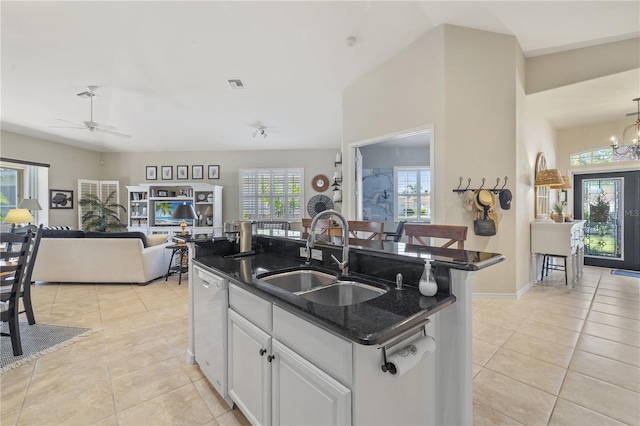 kitchen with ceiling fan with notable chandelier, white dishwasher, sink, white cabinets, and an island with sink